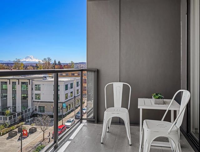 Balcony with two chairs and a table overlooking a city street and a distant mountain.