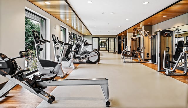 Modern fitness center with cardio machines, weight machines, and rowing machines.