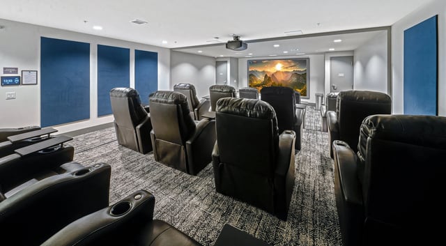 Theater room with plush recliners and a large screen.