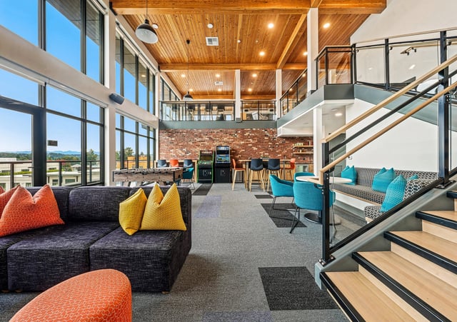 Communal lounge with sofas, foosball table, arcade games, and seating areas.