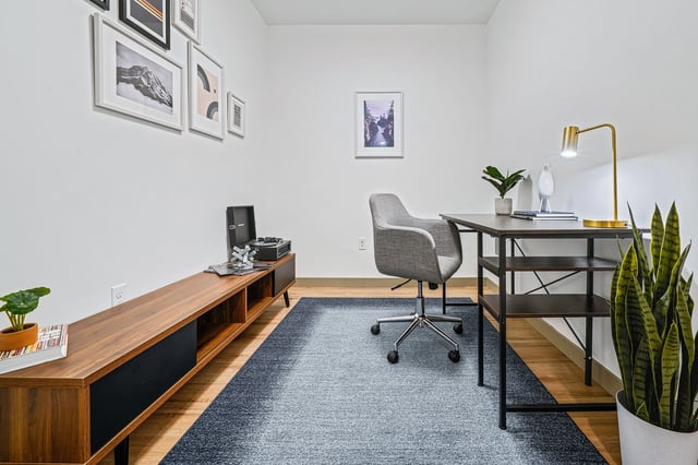 Modern home office with a desk, chair, record player, and artwork.