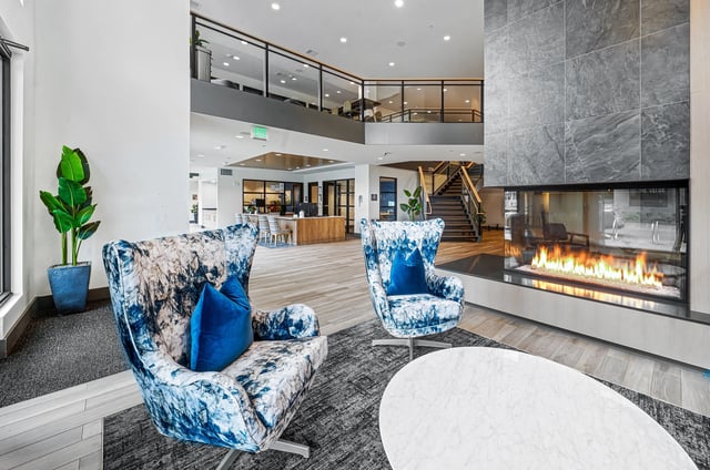 Modern lobby with a fireplace, seating, and a reception desk.