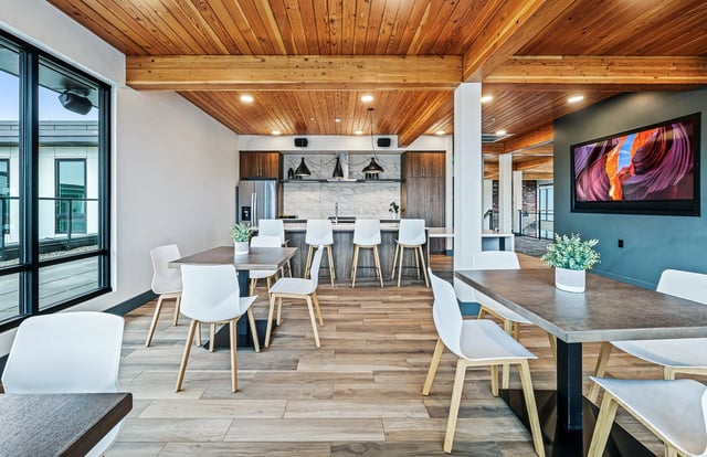 Modern communal kitchen and dining area with wood ceilings and a TV.