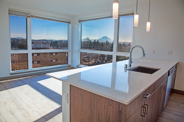 Modern kitchen island with sink and faucet, overlooking large windows with mountain view.