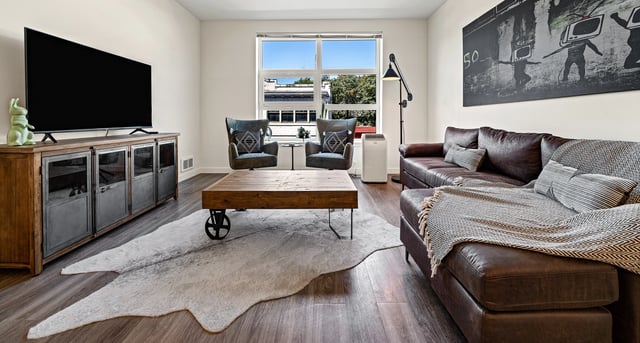 Modern living room with a large TV, leather couch, and coffee table.