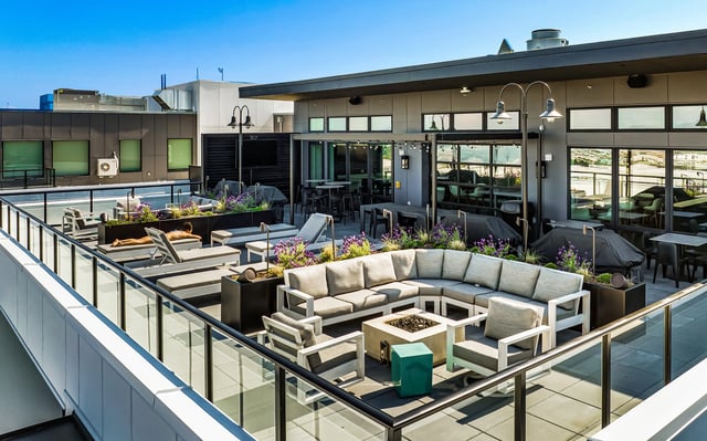 Rooftop lounge area with seating, fire pit, and outdoor kitchen.