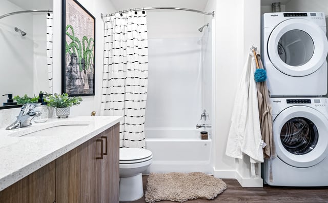 Modern bathroom with stacked washer and dryer, vanity, and tub/shower combo.
