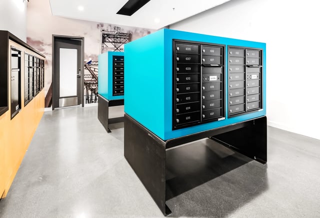 Mailroom with blue and black mailboxes and a large mural on the wall.