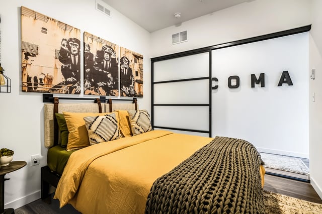 Bedroom with a king-size bed, yellow comforter, and artwork of monkeys.