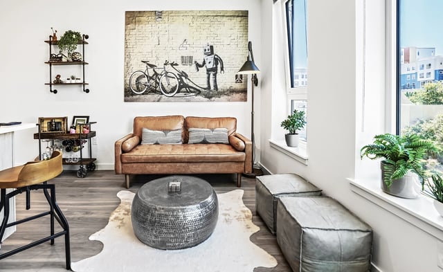 Modern living room with leather sofa, metallic coffee table, and artwork.