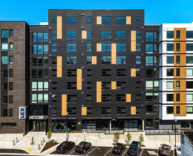 Exterior of modern apartment building with dark facade and wood accents.