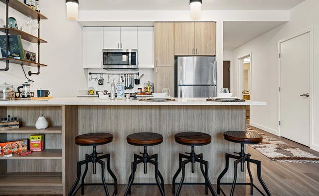 Modern kitchen with a breakfast bar and stools, stainless steel appliances, and ample cabinet space.