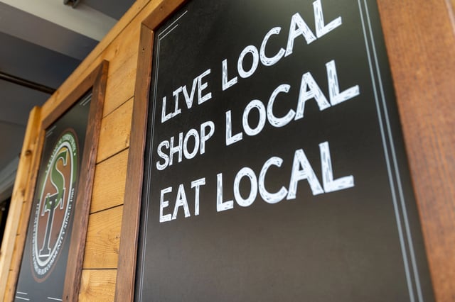 Chalkboard sign with 'Live Local, Shop Local, Eat Local' written in white chalk.