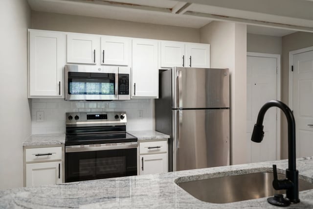 Modern kitchen with stainless steel appliances and white cabinets.