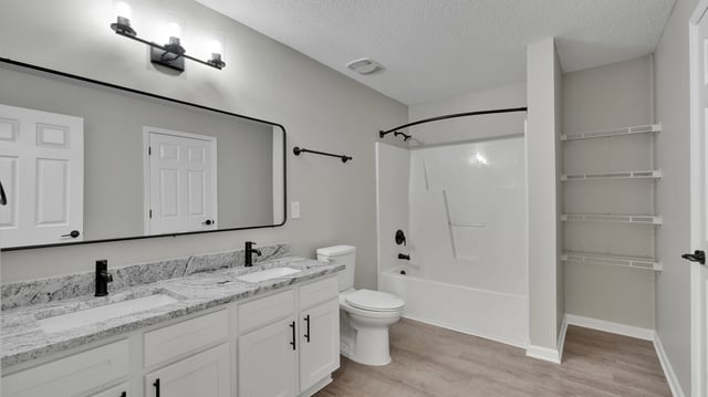 Modern bathroom with a double vanity, toilet, and bathtub.