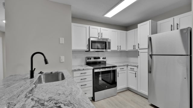 Modern kitchen with white cabinets, stainless steel appliances, and granite countertops.