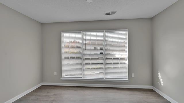 Empty apartment room with a large window covered by blinds.