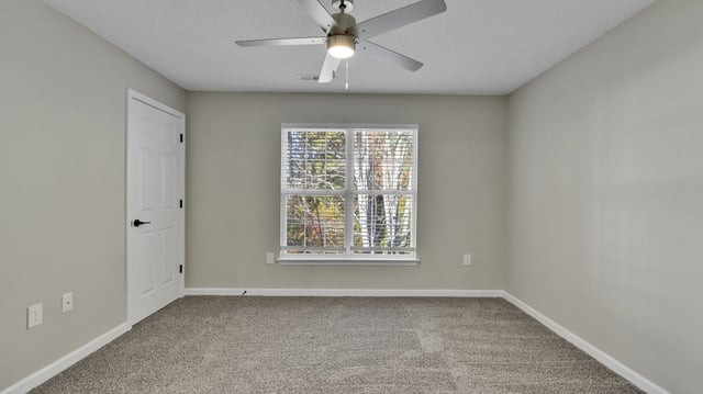Bedroom with a white door, ceiling fan, and window with blinds.