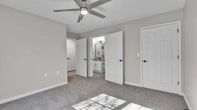 Bedroom with a ceiling fan and doors leading to a bathroom and closet.