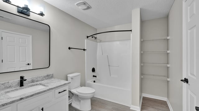 Modern bathroom with vanity, toilet, and bathtub/shower combo.