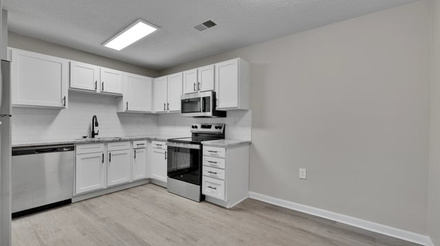 Modern kitchen with white cabinets, stainless steel appliances, and granite countertops.
