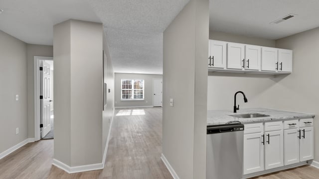 View of a modern apartment kitchen with white cabinets and a granite countertop.