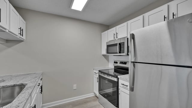 Modern kitchen with stainless steel appliances and white cabinets.
