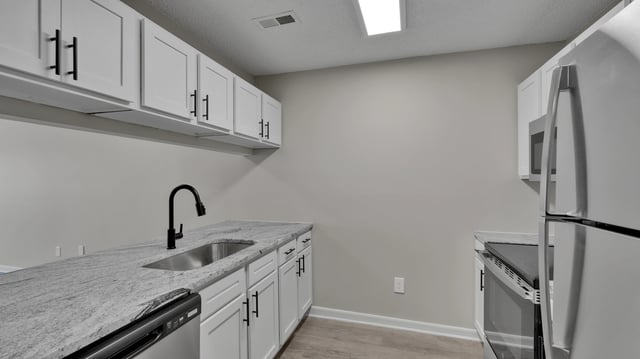 Modern kitchen with white cabinets, granite countertops, and stainless steel appliances.