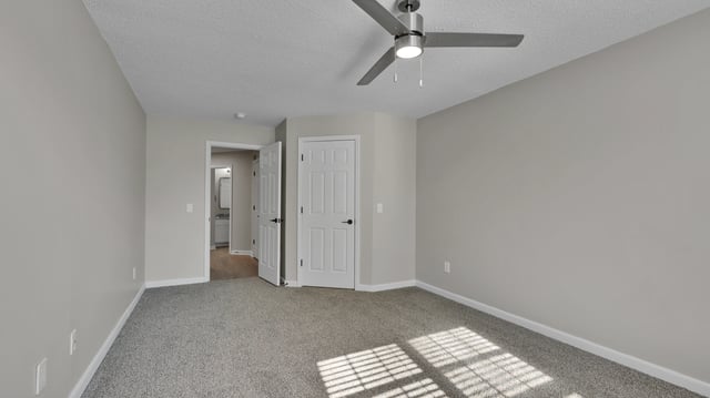 Bedroom with ceiling fan, light grey walls, and a doorway leading to a bathroom.