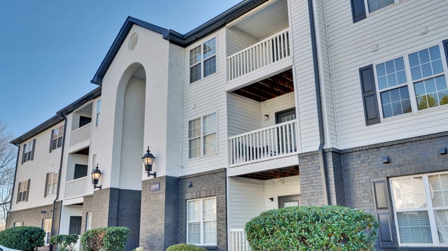 Exterior of apartment building with balconies and white siding.