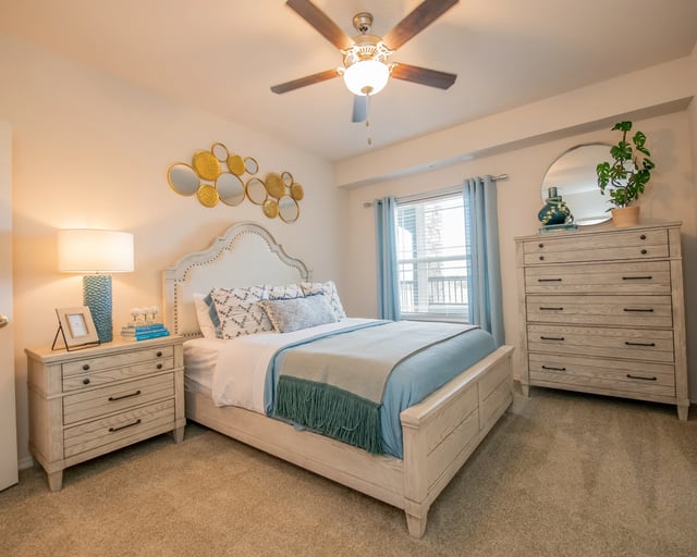 Furnished bedroom with a light wood bed, two dressers, and blue accents