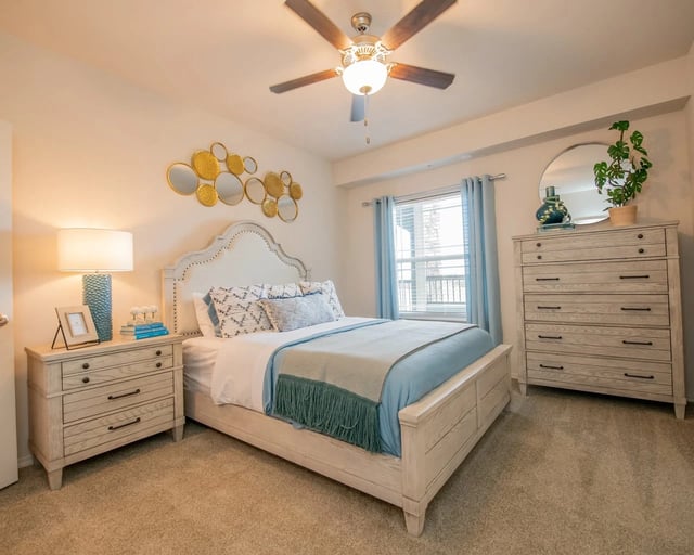 Bedroom with a queen-size bed, nightstand, dresser, and ceiling fan.