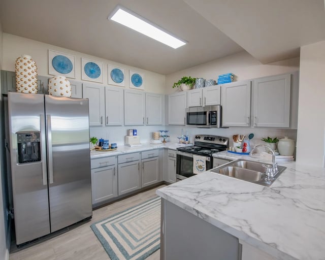 Modern kitchen with stainless steel appliances and light gray cabinets.