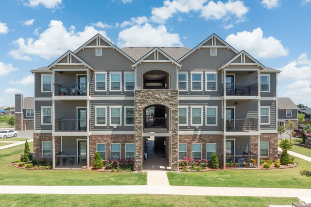 Exterior view of a multi-story apartment building with balconies and brick accents.