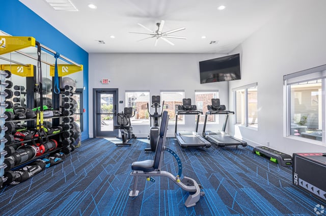 Fitness center with treadmills, ellipticals, weight racks, and a bench.