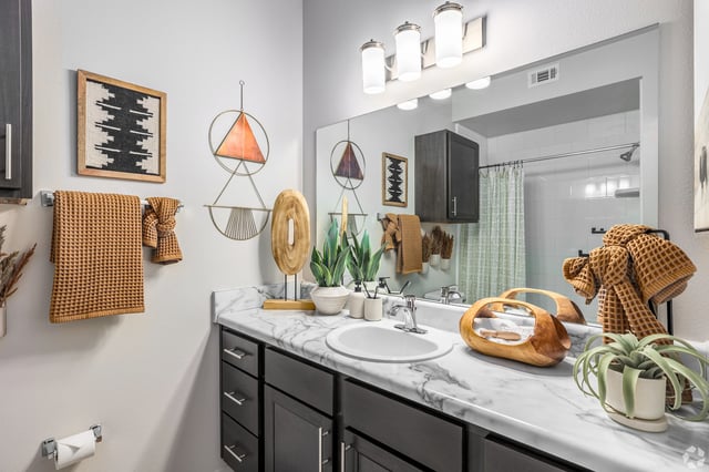 Bathroom with marble countertop, dark wood vanity, and decorative accents.