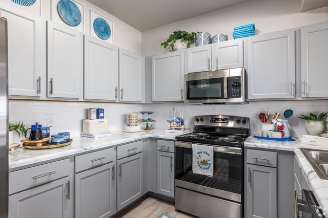 Modern gray kitchen with white subway tile backsplash and stainless steel appliances.