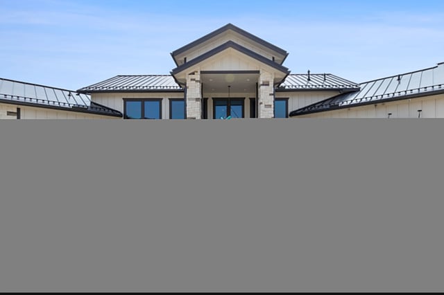 A modern building with a central entrance and a sculpture in front.