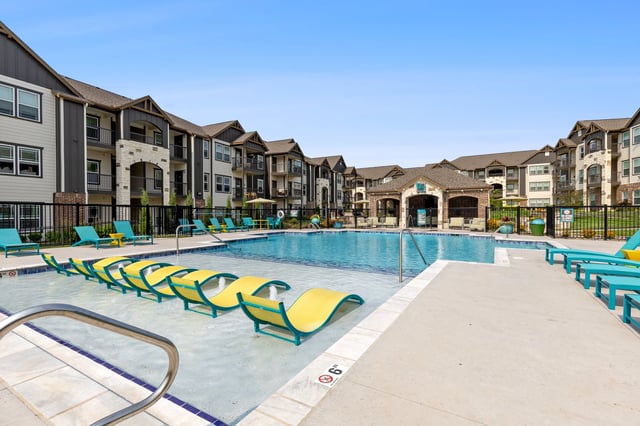 Community pool area with lounge chairs and surrounding apartments