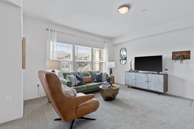 Stylish living room featuring a green sofa, armchair, coffee table, and a TV stand with a TV.