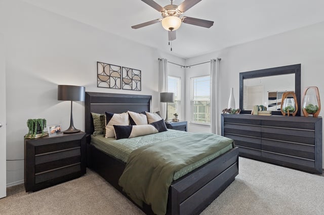 King-sized bed with green and black accents in a master bedroom