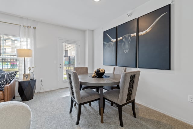 Dining area with a round table and four chairs, featuring a large wall art of a bull.