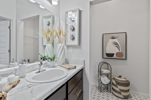 Modern bathroom vanity with marble countertops, chrome faucet, and decorative accents.