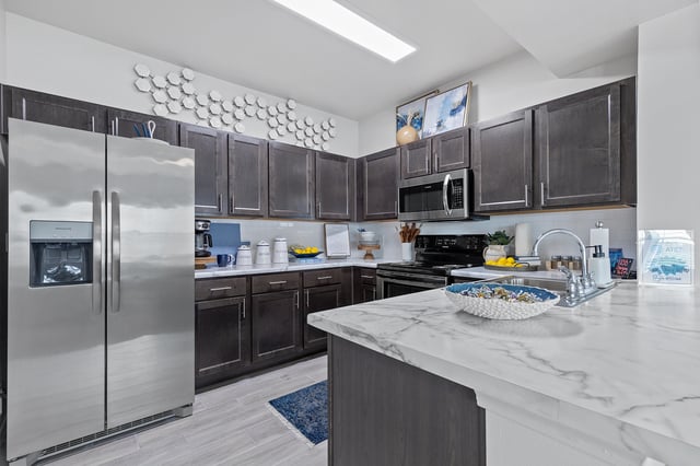Modern kitchen with stainless steel appliances and dark cabinets.