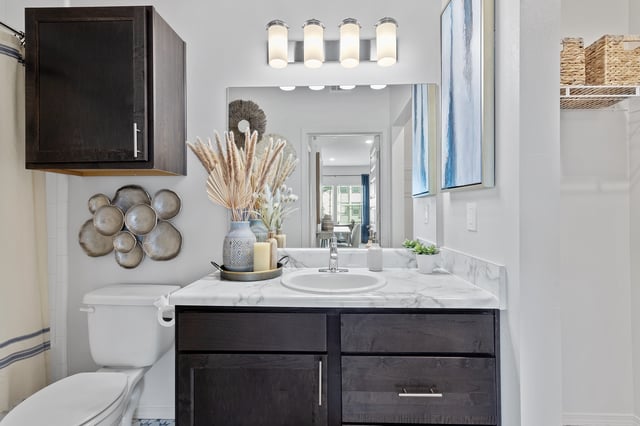 Modern bathroom vanity with marble countertop and dark wood cabinets.