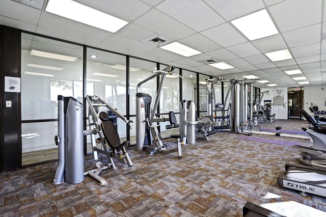 Well-lit fitness center with weight machines and cardio equipment