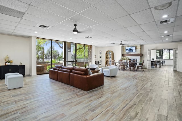 Spacious communal lounge with a leather sectional, modern chairs, and a fireplace.