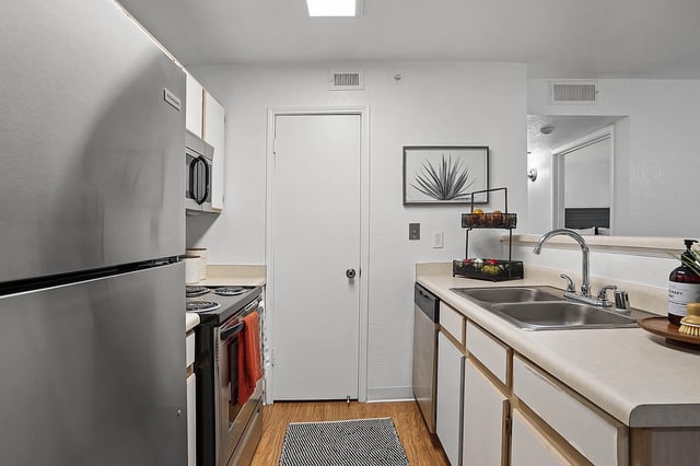 Kitchen with stainless steel refrigerator, oven, sink, and countertops.