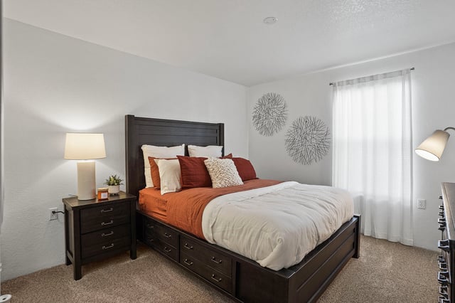Bedroom with a king-size bed, nightstand, lamp, and dresser.