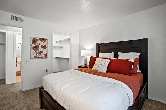 Bedroom with a king-size bed, red and white bedding, and a walk-in closet.